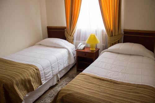 a bedroom with two beds and a lamp and a window at Hotel Terrazas del Mar in Llanquihue