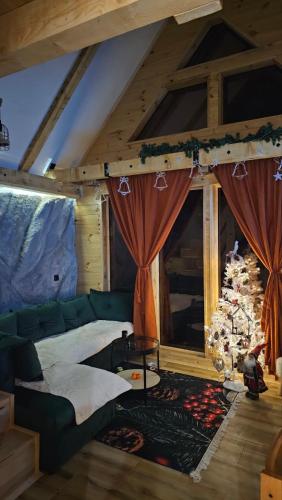 a living room with a green couch and a christmas tree at Chalet Wood Magic in Kolašin