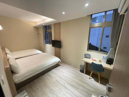a bedroom with a bed and a desk and a window at Shuntai Inn in Fengshan