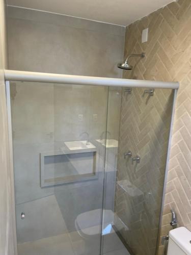 a bathroom with a glass shower with a toilet at Guarajuba Suítes Premium Boutique Hotel in Guarajuba