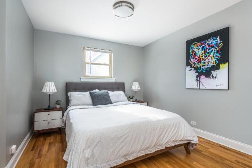 1 dormitorio con 1 cama y una pintura en la pared en The Bright Retreat in Andersonville, en Chicago