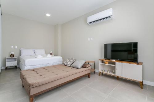 a bedroom with a bed and a couch and a tv at Wi-FIi | 250MB | Sea View | Pool #CA60 in Florianópolis