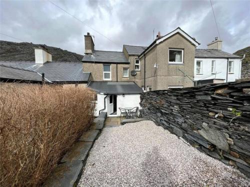 a house with a stone wall and a building at “1-Bed Haven in Snowdonia nr ZipWorld, Snowdon” in Blaenau-Ffestiniog