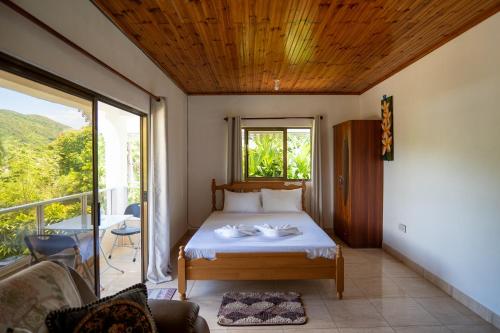 a bedroom with a bed and a balcony at Tropical Beach House in Grand Anse