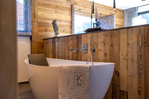 Chalet ORUS - Tirol Kärnten في Irschen: حوض استحمام في الحمام بجدران خشبية