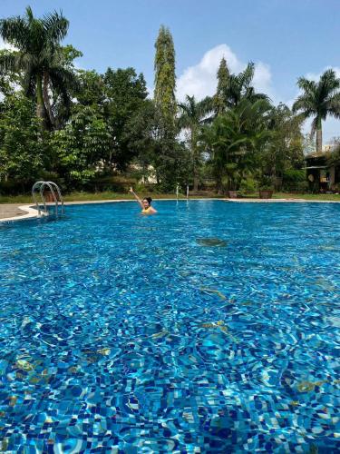 a person swimming in a large pool of blue water at Dukes Den Resort in Lonavala