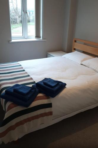 two blue towels sitting on top of a bed at Two bedroom modern flat near central London in London