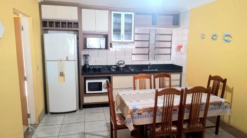 a kitchen with a table and a white refrigerator at Capão da Canoa felicidade in Capão da Canoa