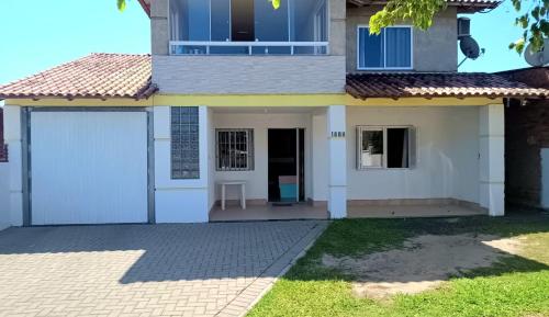 a house with a white garage and a driveway at Capão da Canoa felicidade in Capão da Canoa