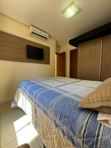 a bedroom with a bed with a blue comforter and a tv at Veredas do Rio Quente 116 in Rio Quente