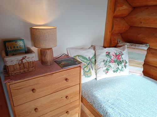 a bedroom with a bed and a dresser with a lamp at Srub Javorná - apartmány Šumava in Javorná