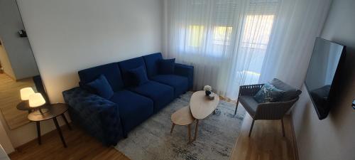 a living room with a blue couch and a table at Zmaj 94 in Bečej