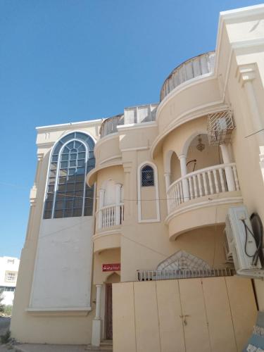 a large white house with a balcony at Viva Hostel Group Muscat in Doha