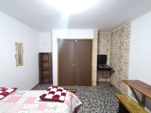 1 dormitorio con 1 cama y puerta de madera en Refugio Kiñeco, en Conguillio