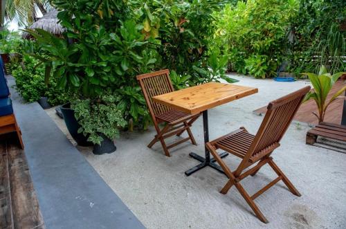 uma mesa de madeira e 2 cadeiras sentadas num pátio em Oceano Beach Vashafaru em Vashafaru