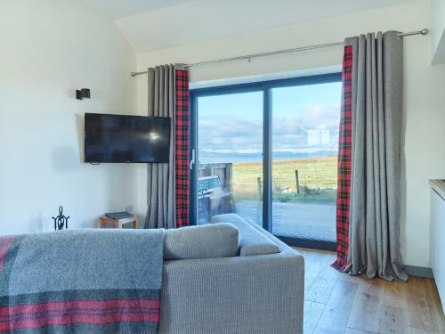 a living room with a couch and a sliding glass door at Monkstadt 1745 Restaurant with Rooms in Portree