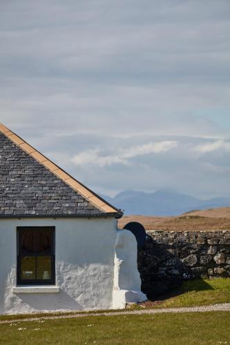 a white house with a window and a stone wall at Monkstadt 1745 Restaurant with Rooms in Portree