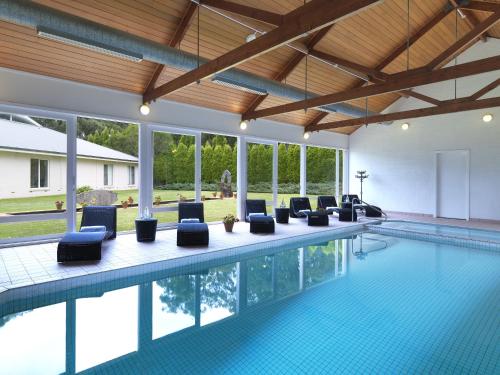 an indoor swimming pool with chairs and a pool house at Lancemore Lindenderry Red Hill in Red Hill
