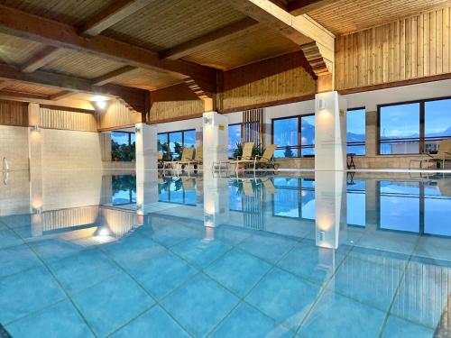 a large swimming pool in a building with windows at GANSL Hotel & Residences in Saalfelden am Steinernen Meer