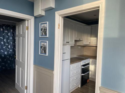 a kitchen with white cabinets and a blue wall at Rossnowlagh Beach House in Donegal