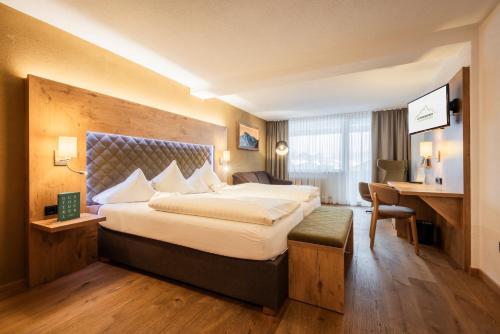 a hotel room with a large bed and a desk at Biohotel Leutascherhof in Leutasch