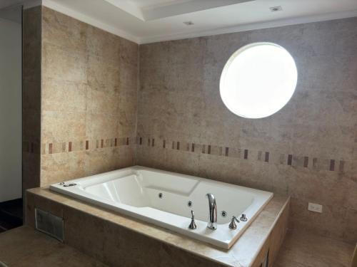 y baño con bañera y ventana redonda. en Suites & Hotel Gonzalez Suarez, en Quito