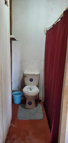 a bathroom with a toilet and a red shower curtain at Coconut House in El Gigante