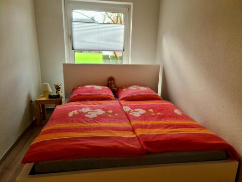 a bed with a red comforter and a window at Ferienwohnung "Erika" Rees am Niederrhein in Rees