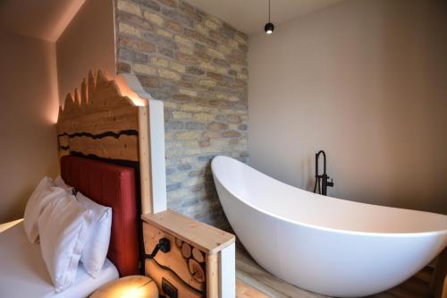 a bathroom with a large white tub and a brick wall at Hotel Cima d'Oro in Ledro