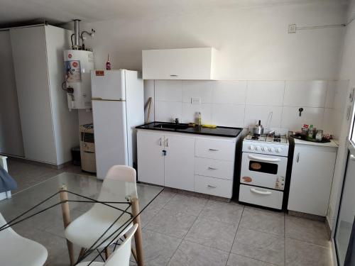 a kitchen with white appliances and a glass table at Alquiler Temporario ZOE 1 Gral Roca - Rio Negro in General Roca