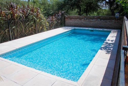 a swimming pool with blue water in a backyard at Cabañas LA ILUSION in La Puerta