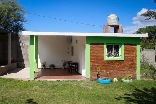 una pequeña casa con techo verde y torre en Cabañas LA ILUSION en La Puerta