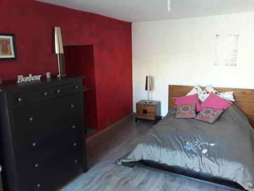 a bedroom with a black dresser and a red wall at Logement du Paquis in Les Mazures