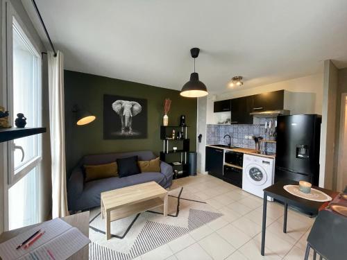 un salon avec un canapé et une cuisine dans l'établissement Le Colorado - Appartement proche Airbus, à Colomiers