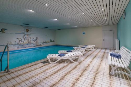 um quarto com uma piscina com cadeiras brancas em Chiemgau Comfort A8 Ferienwohnanlage Oberaudorf mit Hallenbad und Sauna em Oberaudorf