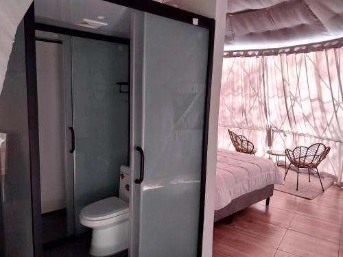a bathroom with a toilet and a bedroom with a bed at Vida Aventura Ranch in Tanques