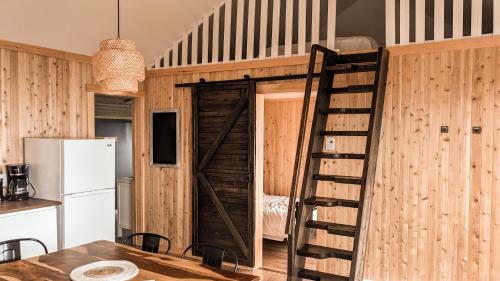 a room with a wooden wall with a door and a ladder at Le Martin Pecheur 2 chambres in Nouvelle