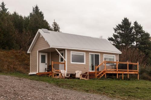 a small house with a porch and chairs on a field at Le Martin Pecheur 2 à 4 personnes in Nouvelle