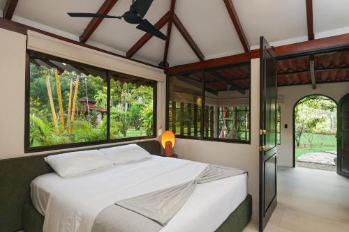 a bedroom with a bed in a room with windows at SCP Corcovado Wilderness Lodge in San Pedrillo
