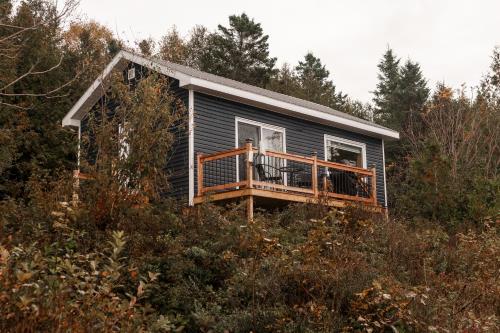 ein winziges Haus mit einer Terrasse auf einem Hügel in der Unterkunft Chalet La Renarde in Nouvelle