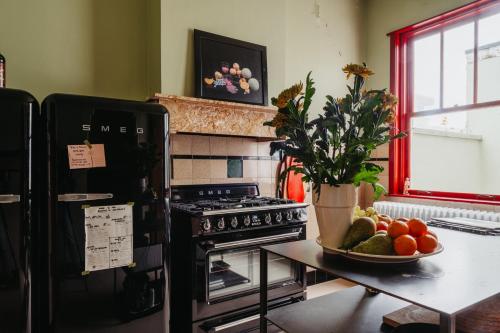 una cocina con fogones y una mesa con un plato de fruta. en Huis Hector Mechiels en Sint-Niklaas