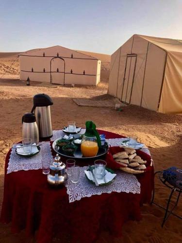 uma mesa com comida e uma tenda no deserto em Itri camp em Zagora