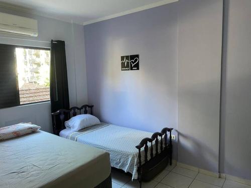 um quarto com 2 camas e uma janela em Apto 2 quadras da Praia do Tombo no Guarujá