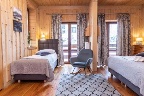 a bedroom with two beds and a chair and a window at Willa u Jadzi in Zakopane