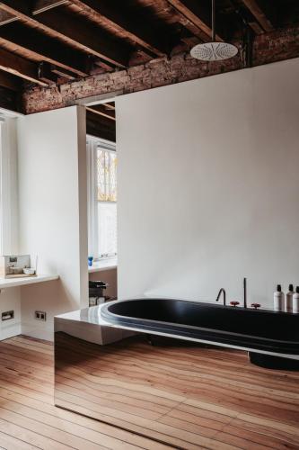 a large black bathtub in a room with a wooden floor at Huis Hector Mechiels ROOM in Sint-Niklaas