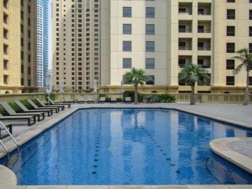 a large blue swimming pool in front of buildings at 2BR Luxury Apartment Marina View in Dubai