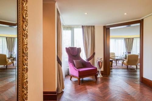 a living room with a pink chair and a mirror at Hilton Frankfurt Gravenbruch in Gravenbruch