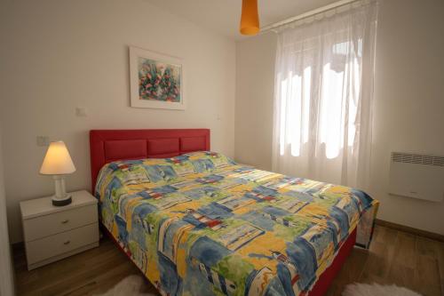 ein Schlafzimmer mit einem Bett mit einer bunten Decke und einem Fenster in der Unterkunft Apartman Mersab in Živogošće