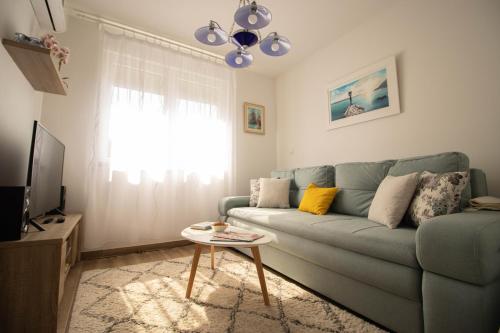 a living room with a blue couch and a table at Apartments Mersab in Živogošće