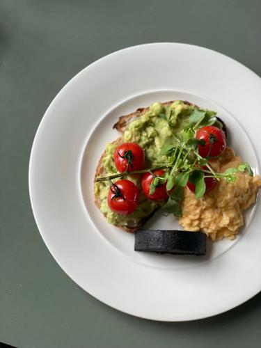a white plate of food with tomatoes on it at Monkstadt 1745 Restaurant with Rooms in Portree